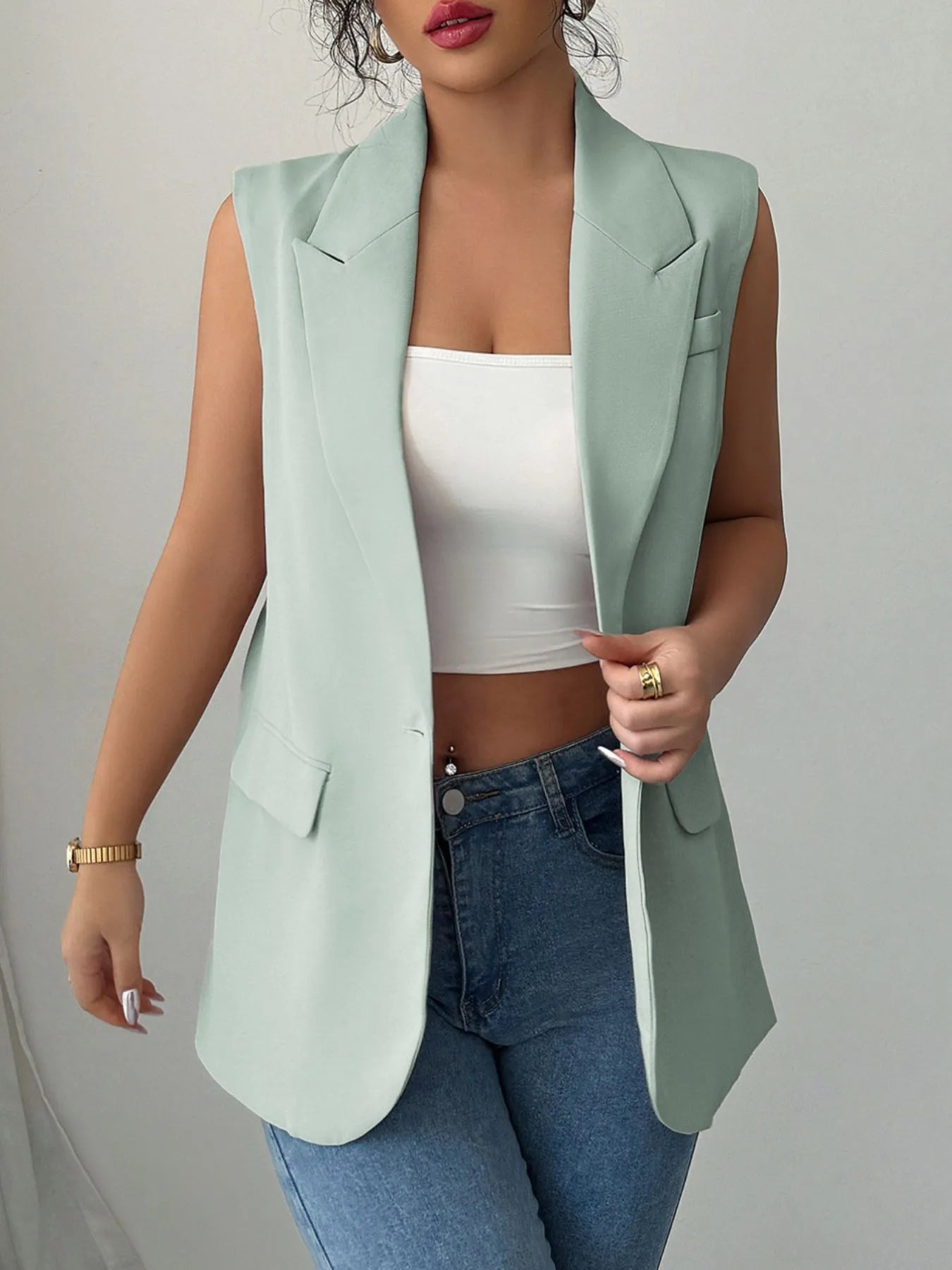 One Button Sleeveless Blazer in mint green worn over a white top and blue jeans, showcasing a stylish layered look.