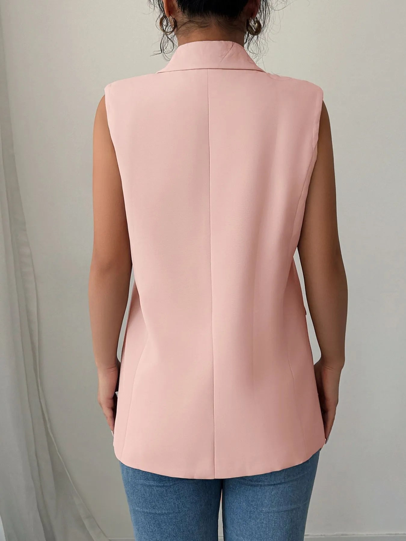 Back view of a model wearing the One Button Sleeveless Blazer in pink, showcasing its sleek design and modern style.